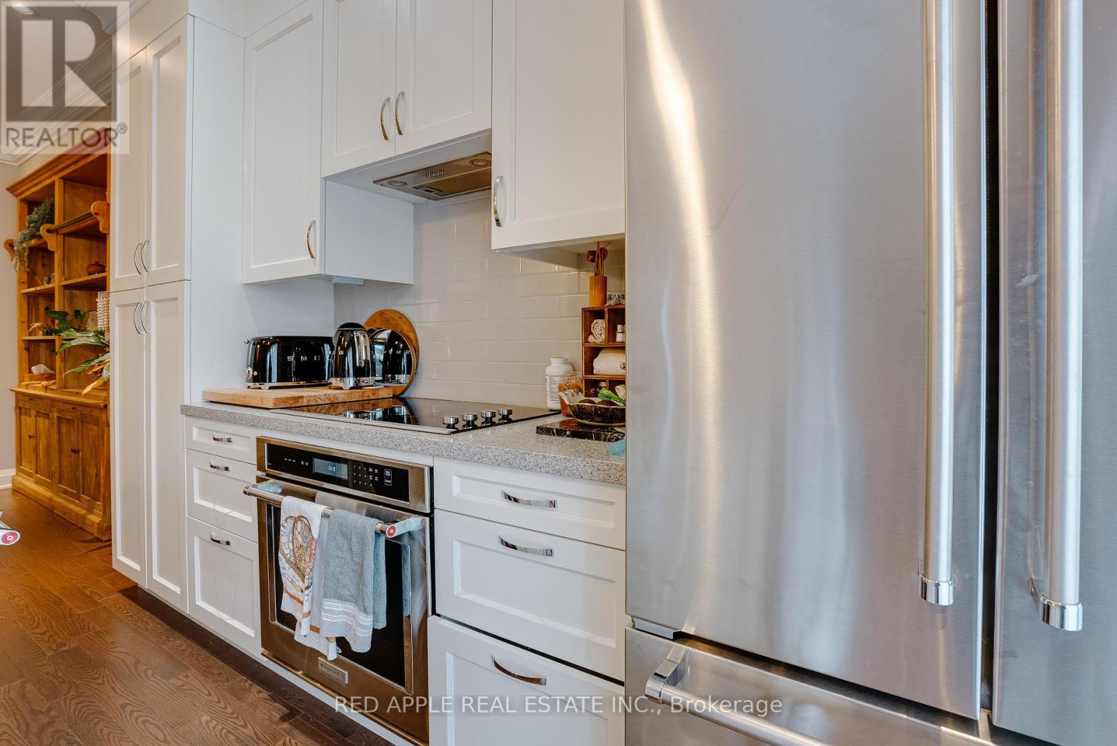 A modern kitchen with a stainless steel refrigerator and white cabinets.