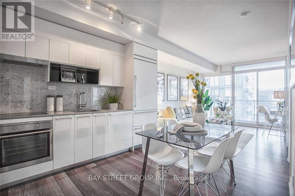 A modern kitchen with white cabinets and a glass dining table.