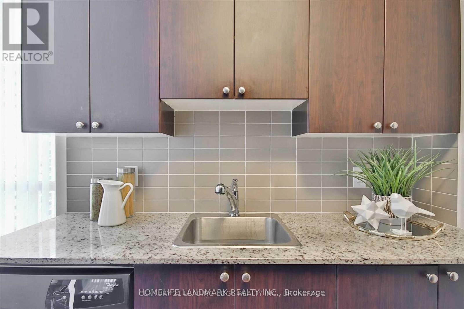 A kitchen with a sink and a coffee pot on the counter.