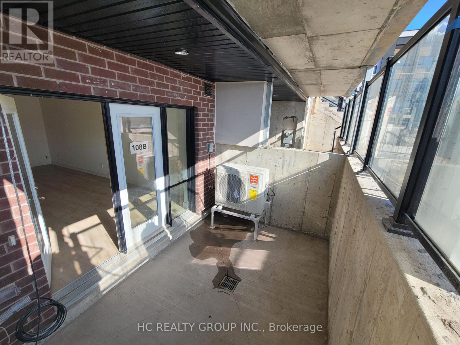 A balcony with a glass door and a concrete floor.