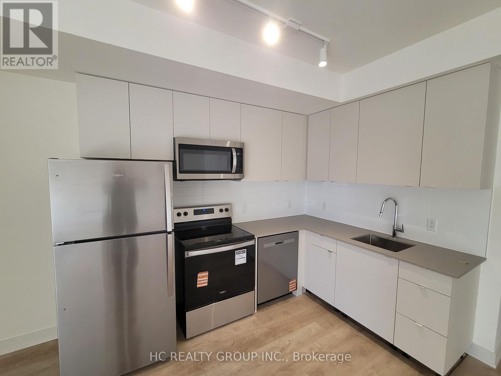 A kitchen with white cabinets and a stainless steel refrigerator.