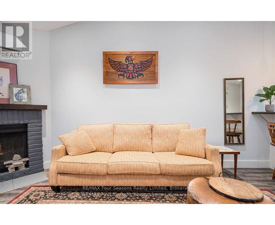 A living room with a tan couch and a wooden bird painting on the wall.