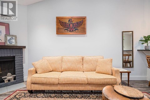 A living room with a tan couch and a wooden bird painting on the wall.