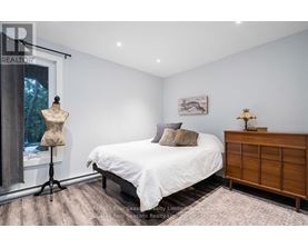A bedroom with a white bed and a wooden dresser.
