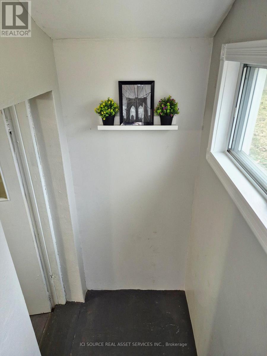 A hallway with a window and a shelf with two potted plants.