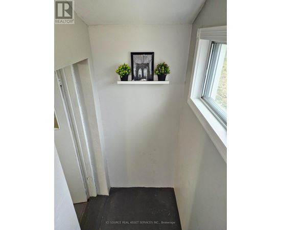 A hallway with a window and a shelf with two potted plants.
