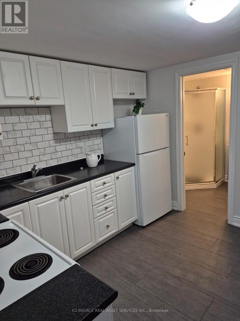 A kitchen with white cabinets and a black countertop.