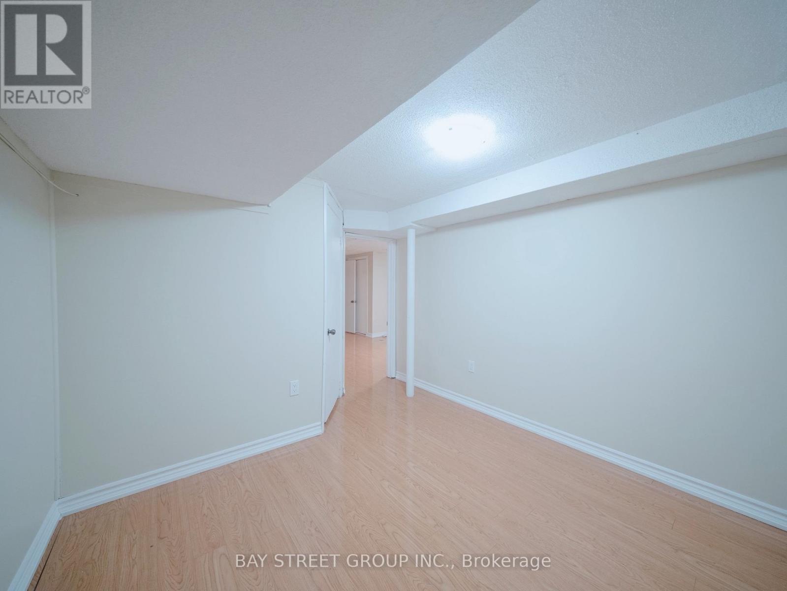A spacious room with wooden flooring and white walls, with a doorway leading to another room.