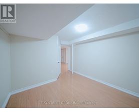A spacious room with wooden flooring and white walls, with a doorway leading to another room.