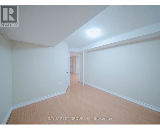A spacious room with wooden flooring and white walls, with a doorway leading to another room.