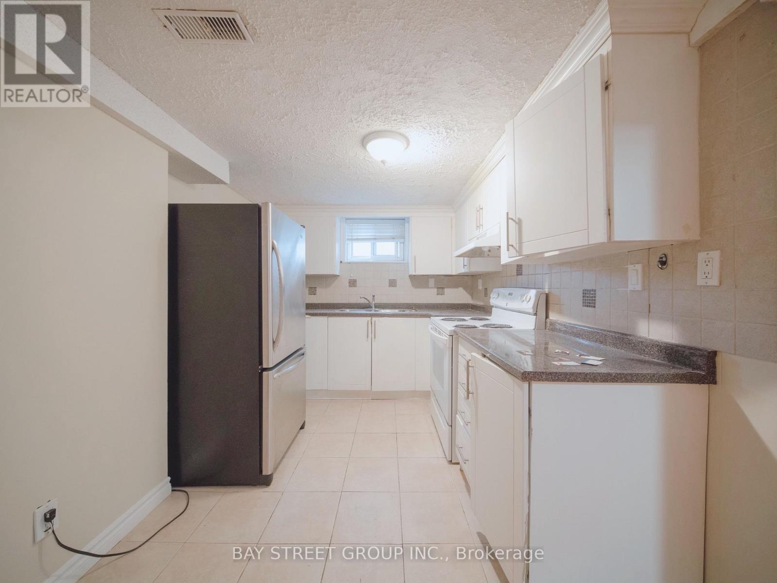 A kitchen with white cabinets and a black refrigerator.