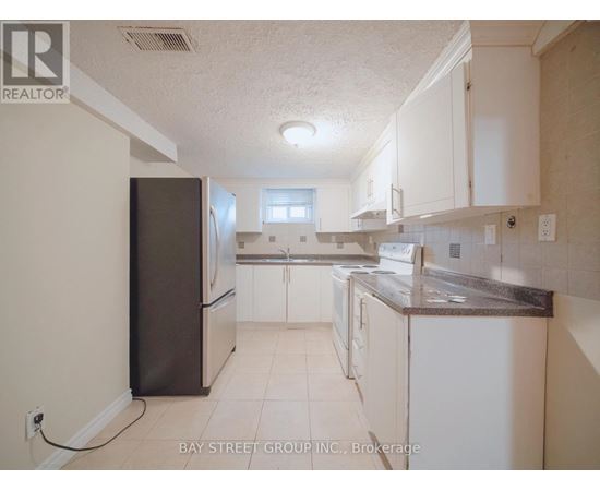 A kitchen with white cabinets and a black refrigerator.