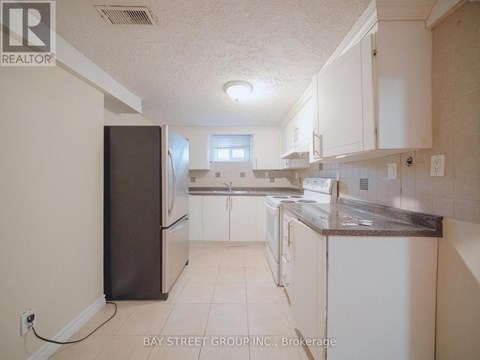 A kitchen with white cabinets and a black refrigerator.