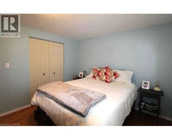A bedroom with a bed, nightstand, and a door.