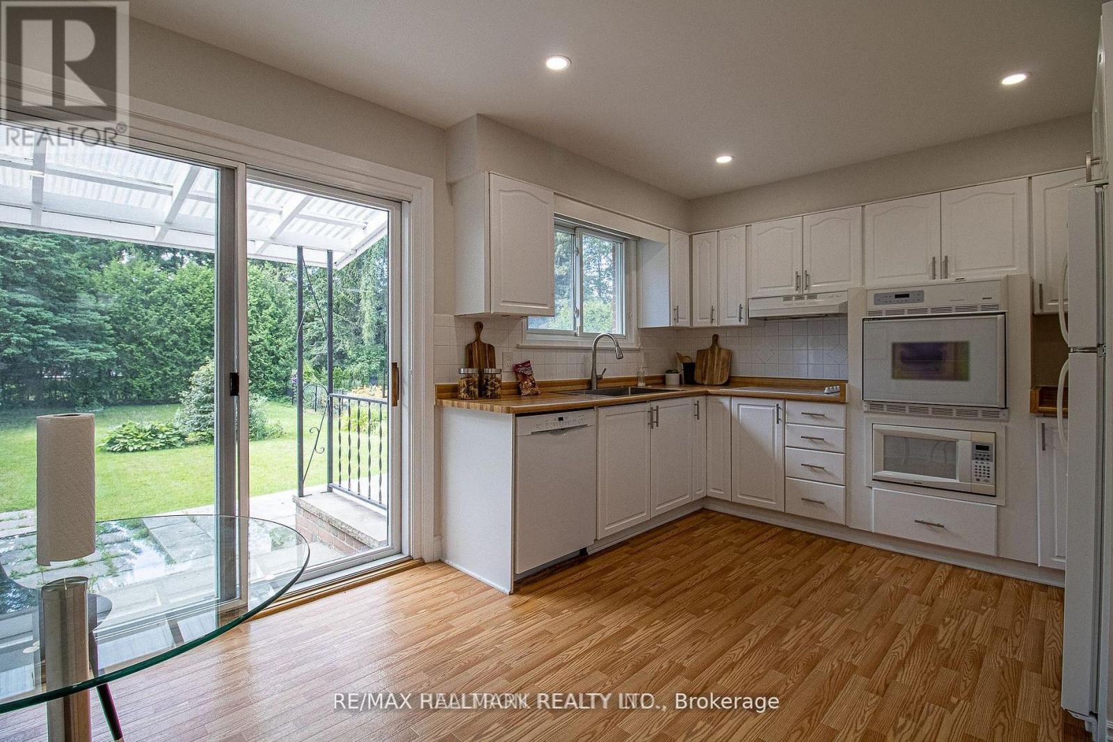 A kitchen with white cabinets and wooden floors.