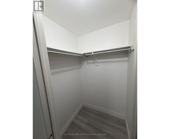 A small, empty walk-in closet with a grey carpet.