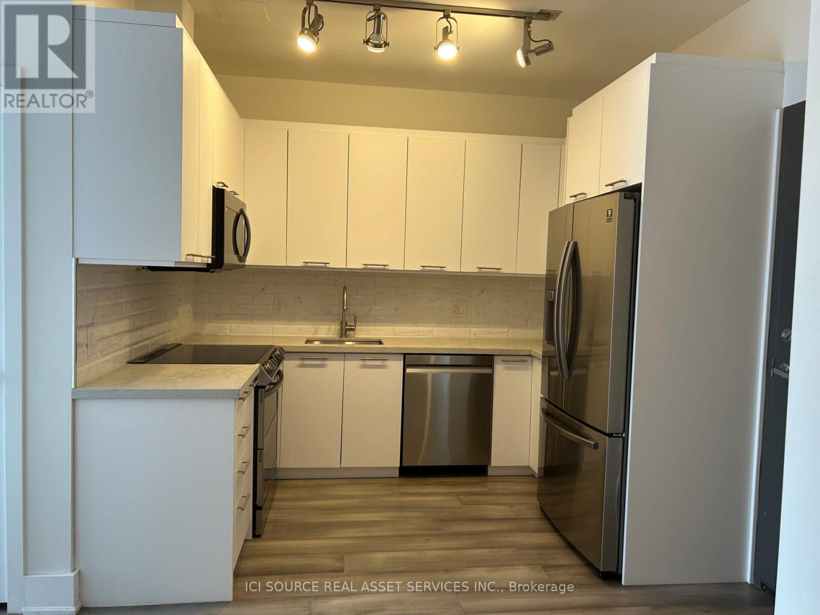 A kitchen with white cabinets and a stainless steel refrigerator.