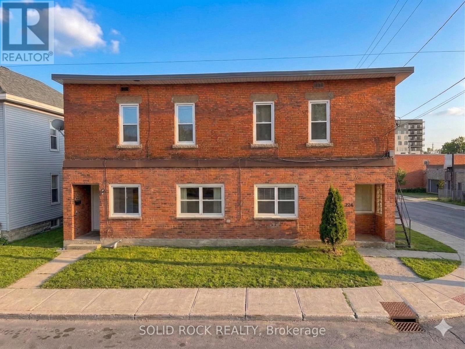 A red brick house with a green lawn in front.
