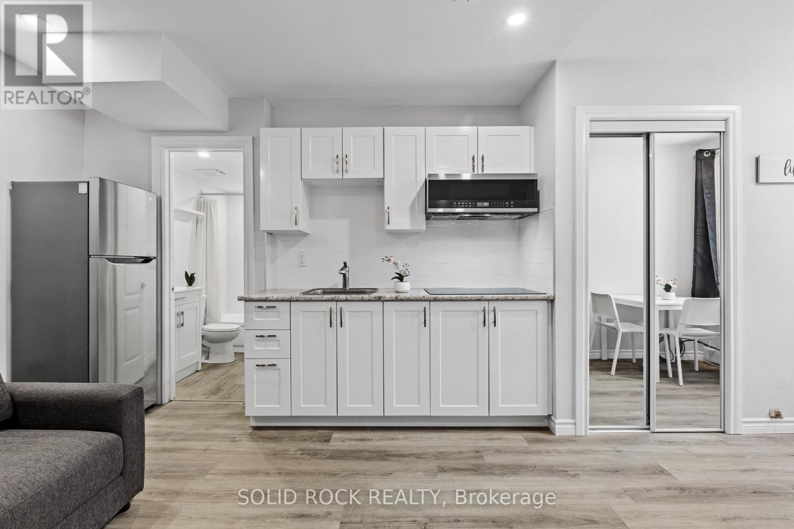 A modern kitchen with white cabinets and a grey couch.