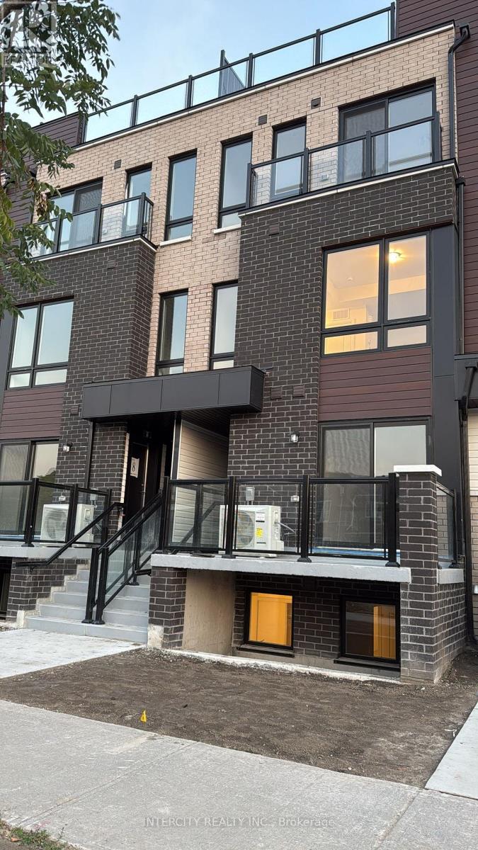 A modern brick building with a balcony and a small garden in front.