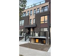 A modern brick building with a balcony and a small garden in front.