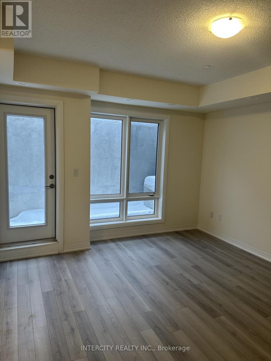 A room with a door, a window and a wooden floor.