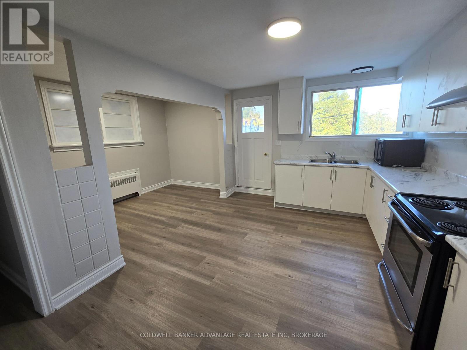 A kitchen with wood flooring and white appliances.