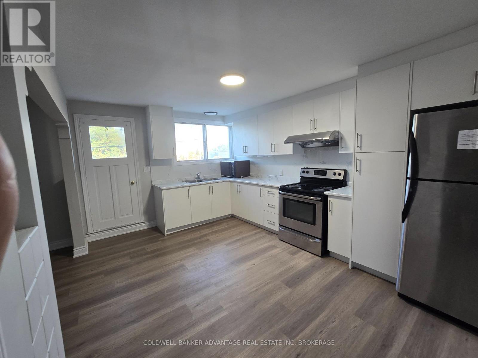 A kitchen with white cabinets and a wooden floor.