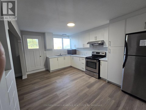 A kitchen with white cabinets and a wooden floor.