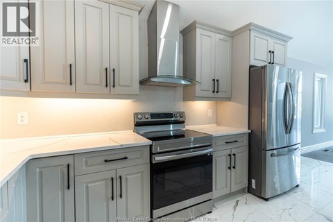A kitchen with white cabinets and a stainless steel refrigerator.