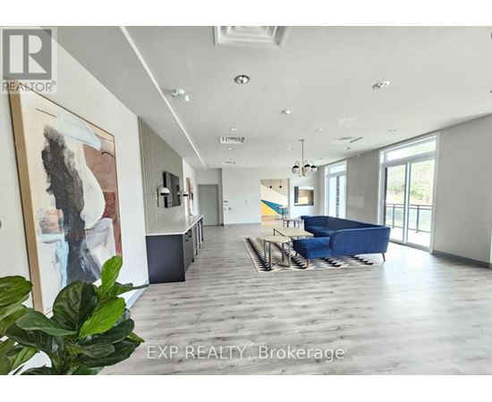 A living room with a blue couch and a painting on the wall.