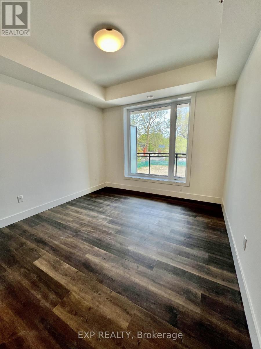 A room with wooden flooring and a window overlooking a fence.