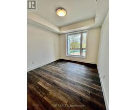 A room with wooden flooring and a window overlooking a fence.