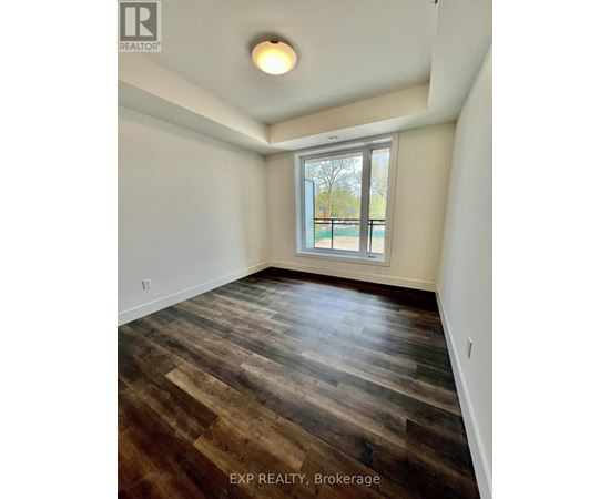 A room with wooden flooring and a window overlooking a fence.