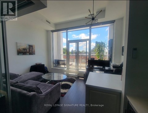 A living room with a grey couch and a table in front of a large window.