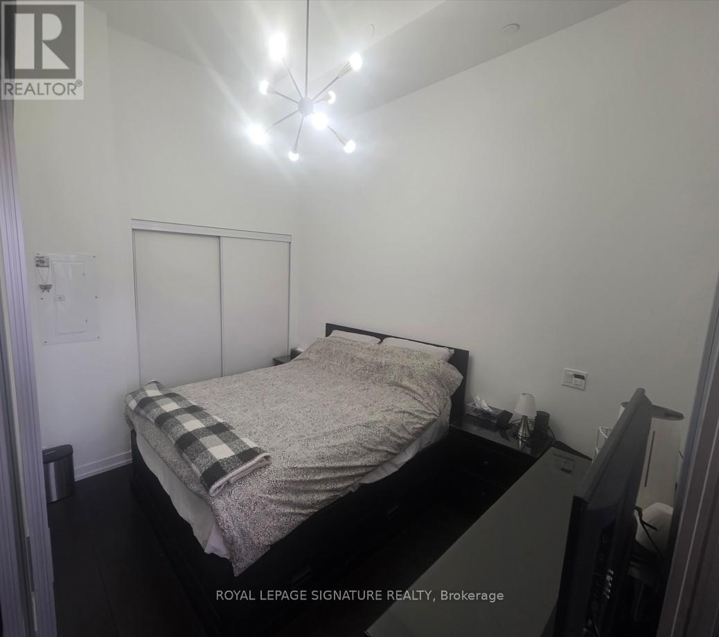 A bedroom with a bed, nightstand, and a chandelier.