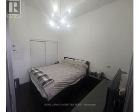 A bedroom with a bed, nightstand, and a chandelier.