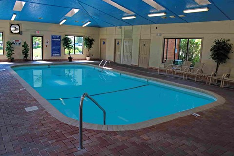 A large indoor swimming pool with a blue ceiling and brick border.
