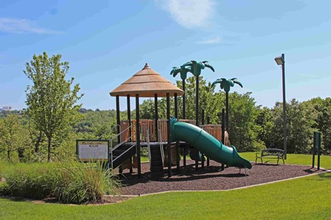 A playground with a green slide and a brown gazebo.