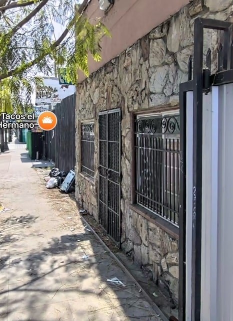 A stone wall with a metal gate and a sign that says Tacos El Tremendo.
