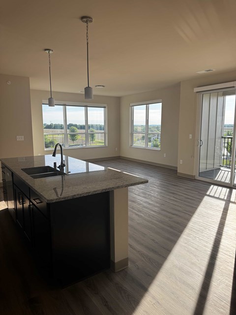 A kitchen with a sink and a countertop with a window in the background.
