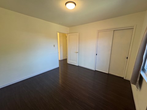 A room with wooden floors and white walls with two doors.