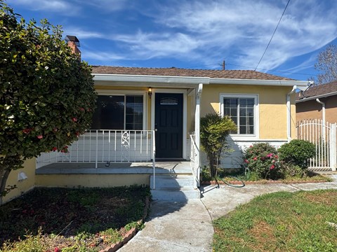 A yellow house with a black door and a small front porch.