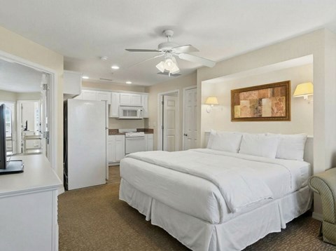 A bedroom with a large bed and a ceiling fan.