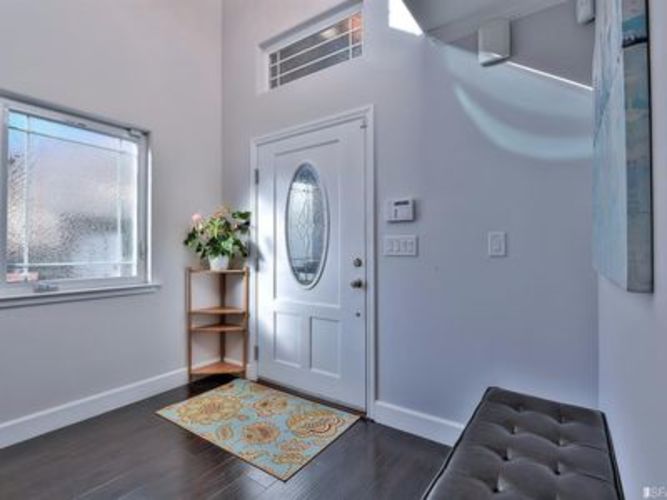A room with a door, a window, a rug, and a bench.