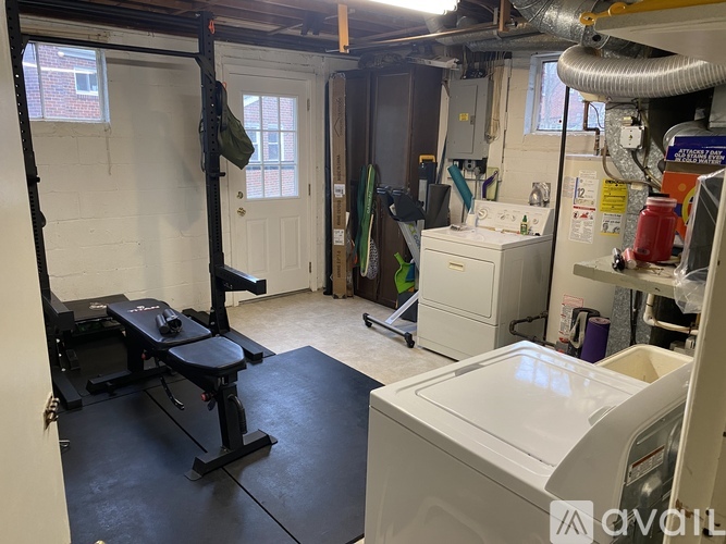 A gym room with a squat rack, a bench, and a washing machine.
