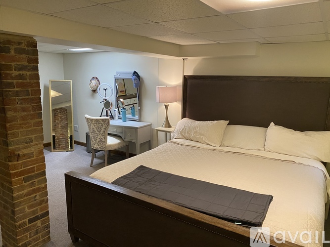 A bedroom with a large bed and a desk with a chair.
