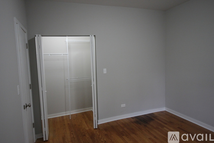 A room with a white door and a white wall with a wooden floor.
