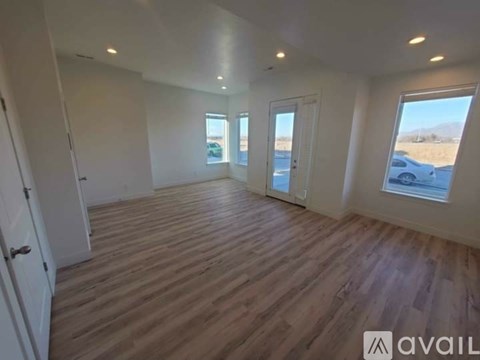 A spacious room with wooden flooring and large windows.