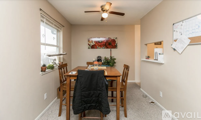 A dining room with a table set for two and a ceiling fan.